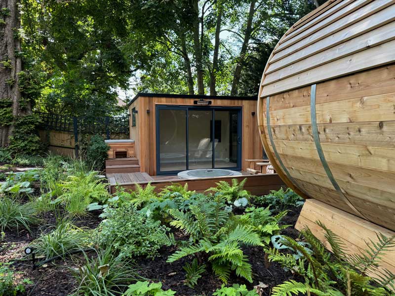 garden room in a woodland setting with decking and built in seating to the front of it