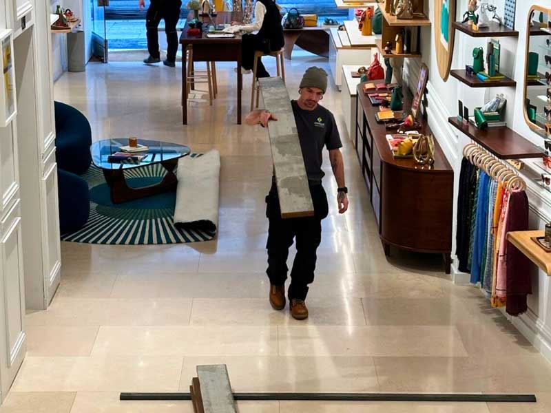 landscaper from Unique Projects carrying decking boards through a Bond Street store in readiness for installing a roof garden