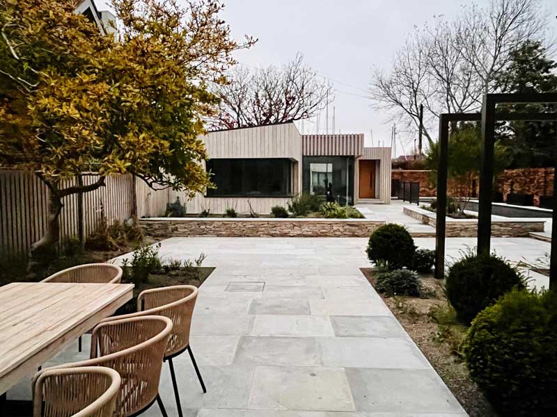 a natural limestone patio is framed by low raised borders filled with interesting plants