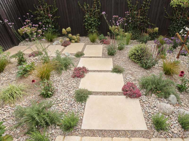 limestone pavers form a pathway of stepping stones through a tastefully planted, gravel mulched border