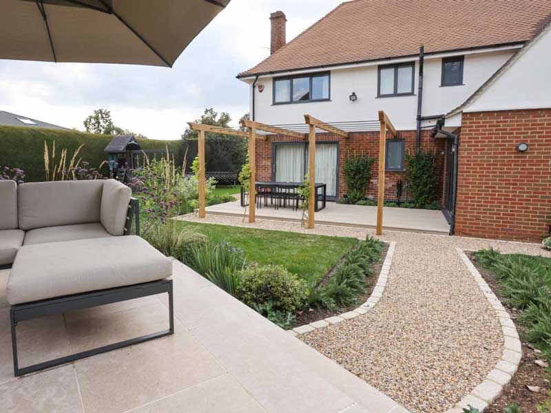 back garden designed by Judy Shardlow featuring limestone patio with path leading to outdoor dining terrace which sits adjacent to the property