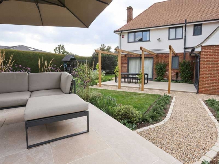 tumbled limestone patio with relaxing furniture and views over a beautifully designed mid sized garden