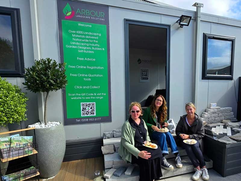 three garden designers relaxing on the steps of Arbour Landscape Solutions samples shed